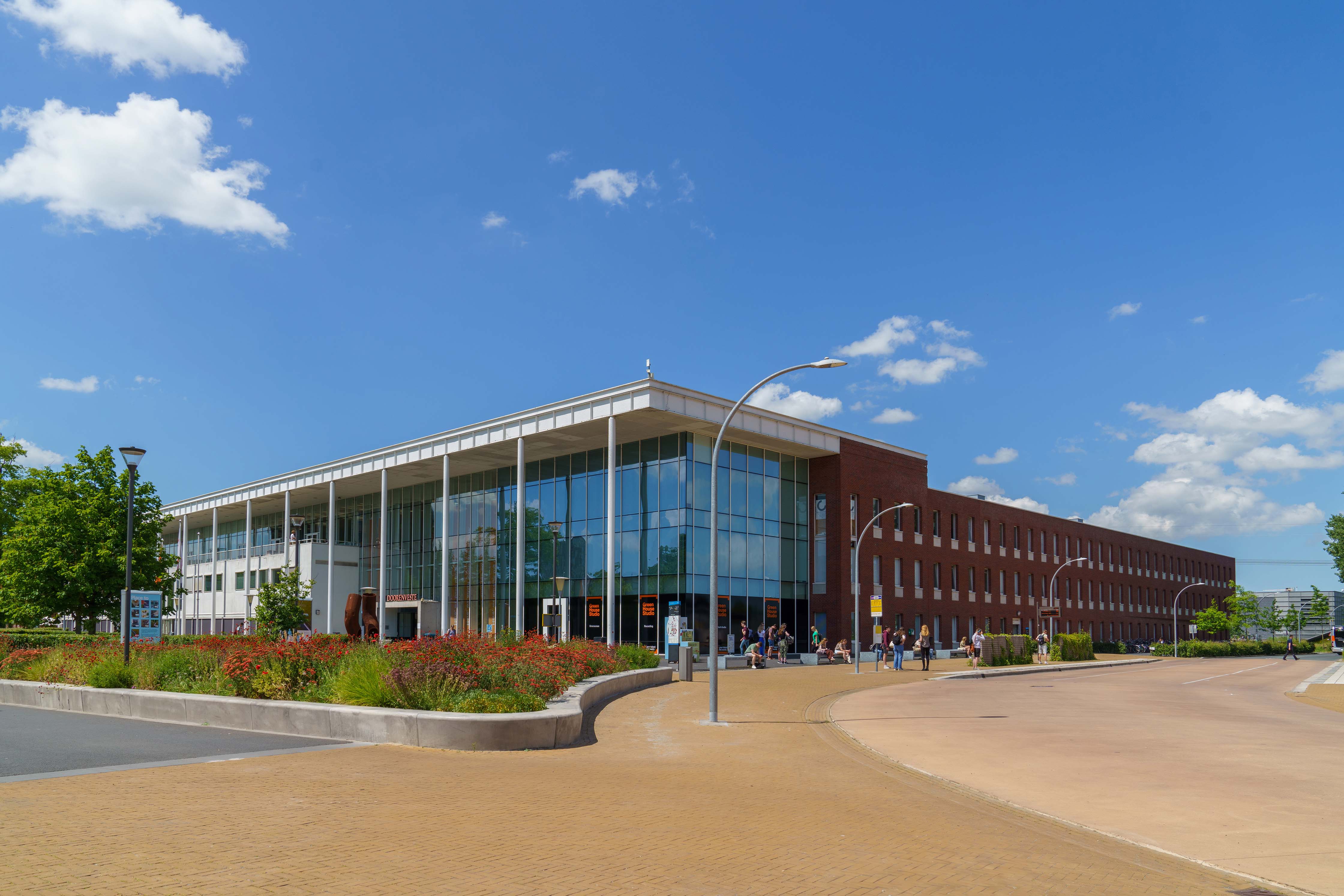 Noorderpoort onderwijsgebouw aan Zernikeplein 11 in Groningen met studenten bij de ingang op een zonnige dag