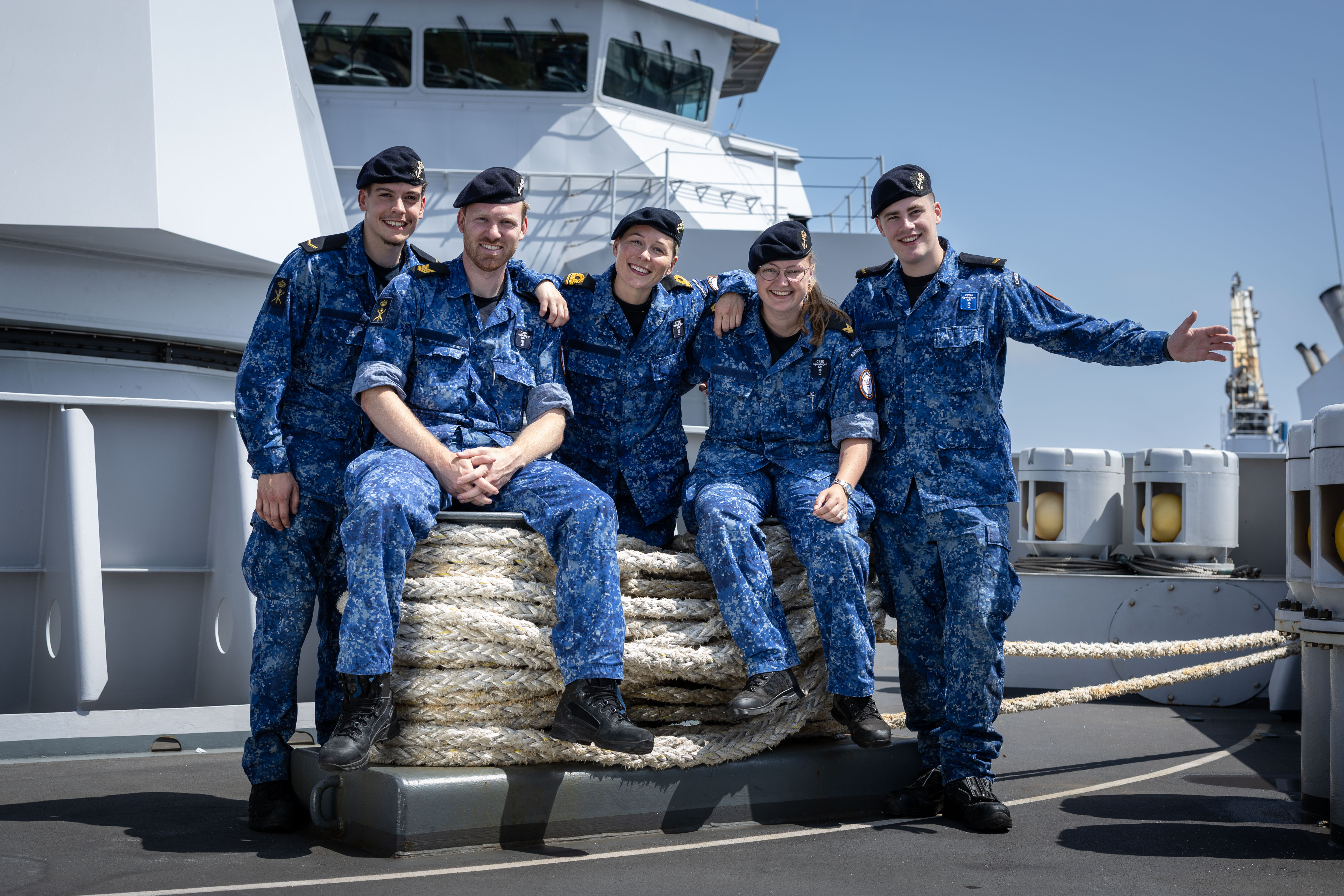 Vijf studenten in maritieme opleiding poseert samen op het dek van een opleidingsschip