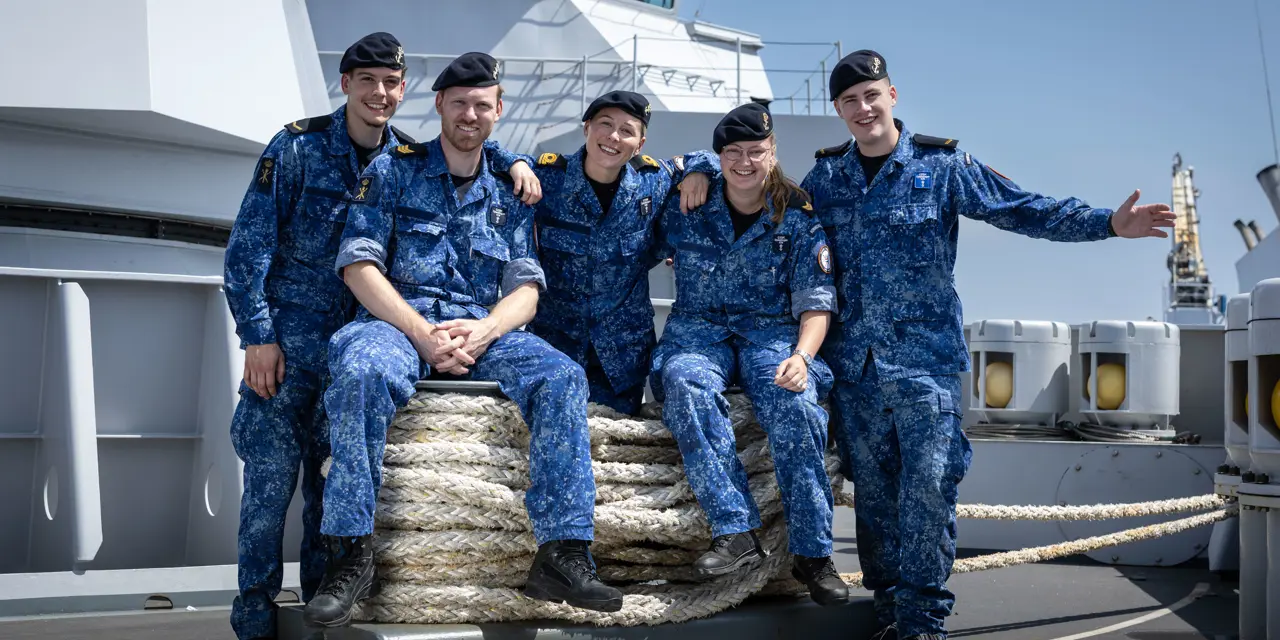 Vijf studenten in maritieme opleiding poseert samen op het dek van een opleidingsschip