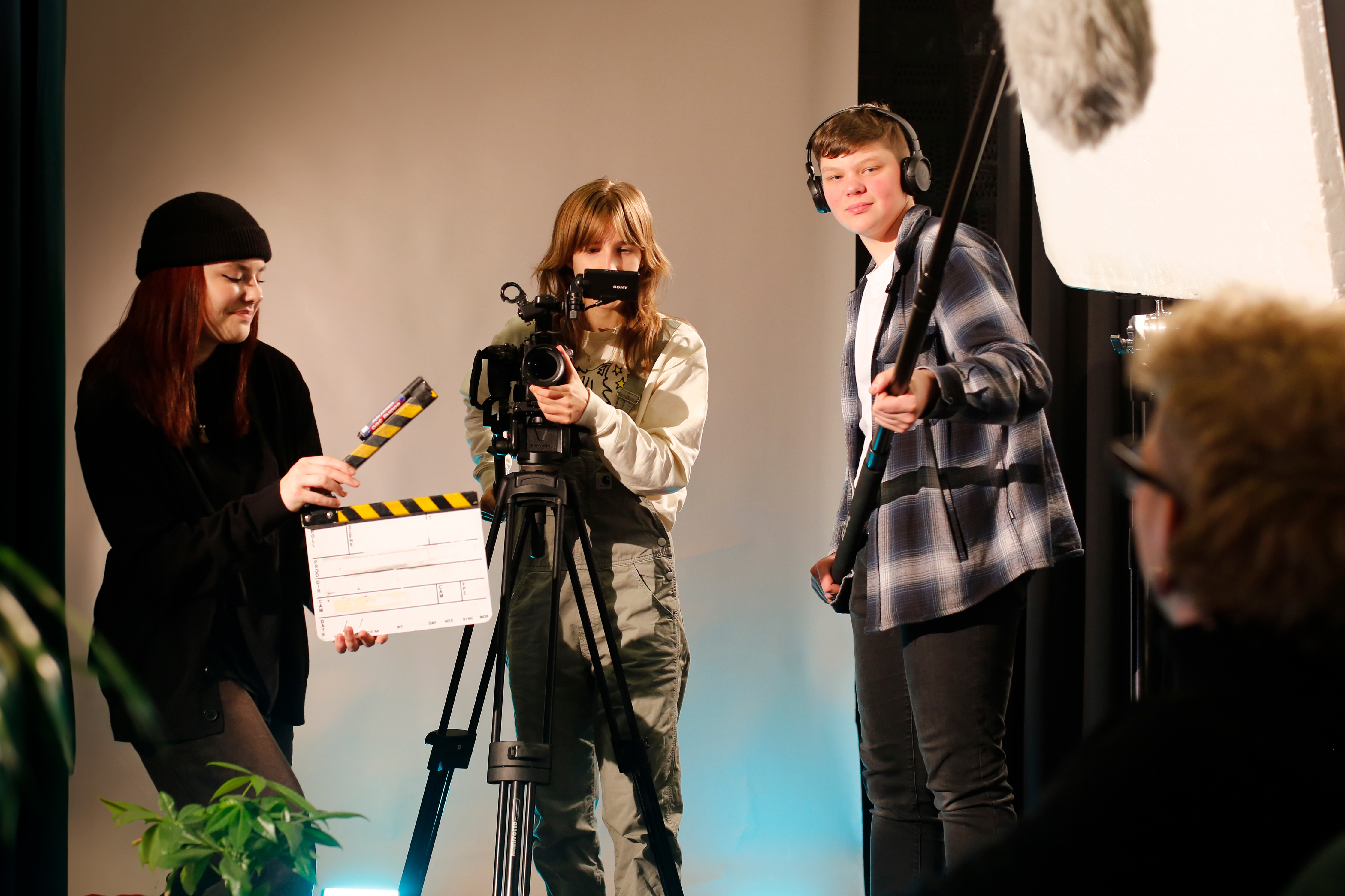 Studenten werken samen bij het maken van een video-opname met camera, klapbord en microfoon.