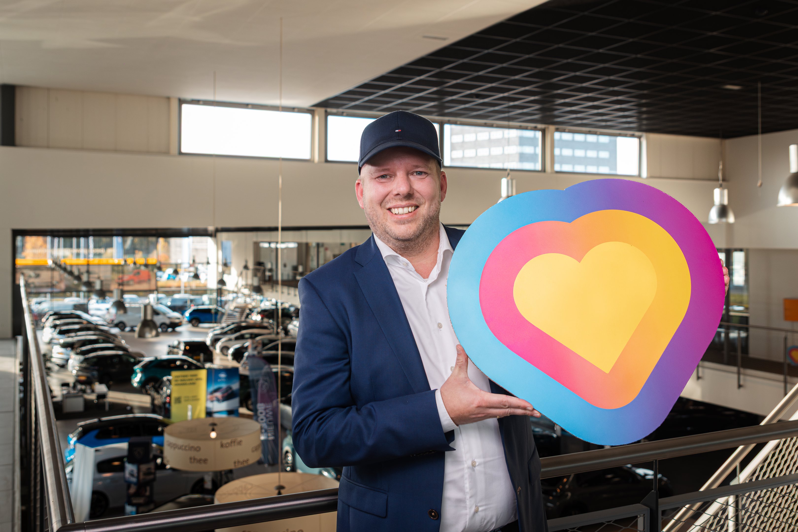 Professioneel in een zakelijke omgeving houdt een man een kleurrijk symbool met een hartvorm vast ter promotie van betrokkenheid.