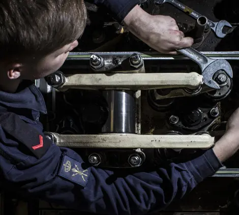 Technische student werkt aan marinetechniek en onderhoudt complexe machineonderdelen aan boord.