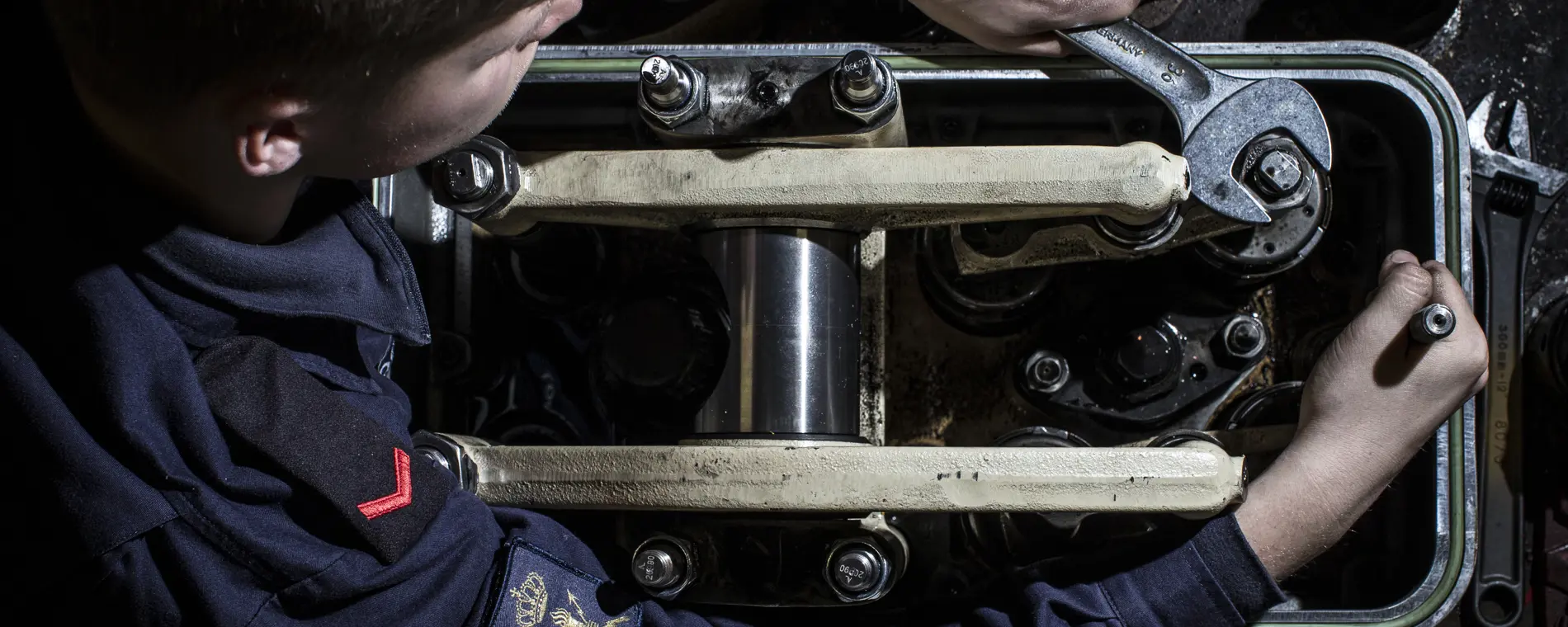 Technische student werkt aan marinetechniek en onderhoudt complexe machineonderdelen aan boord.