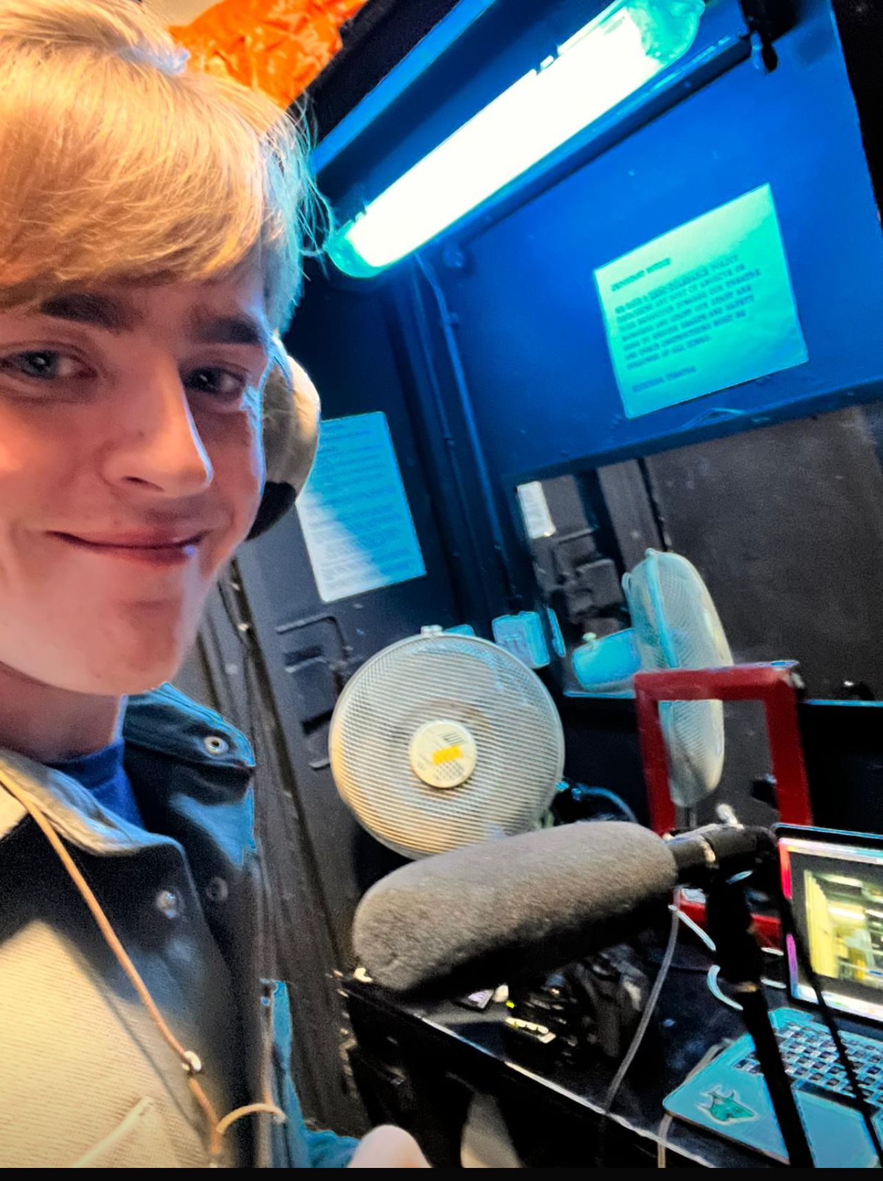 Student neemt een voice-over op in een geluidsstudio met professionele microfoon en scherm.