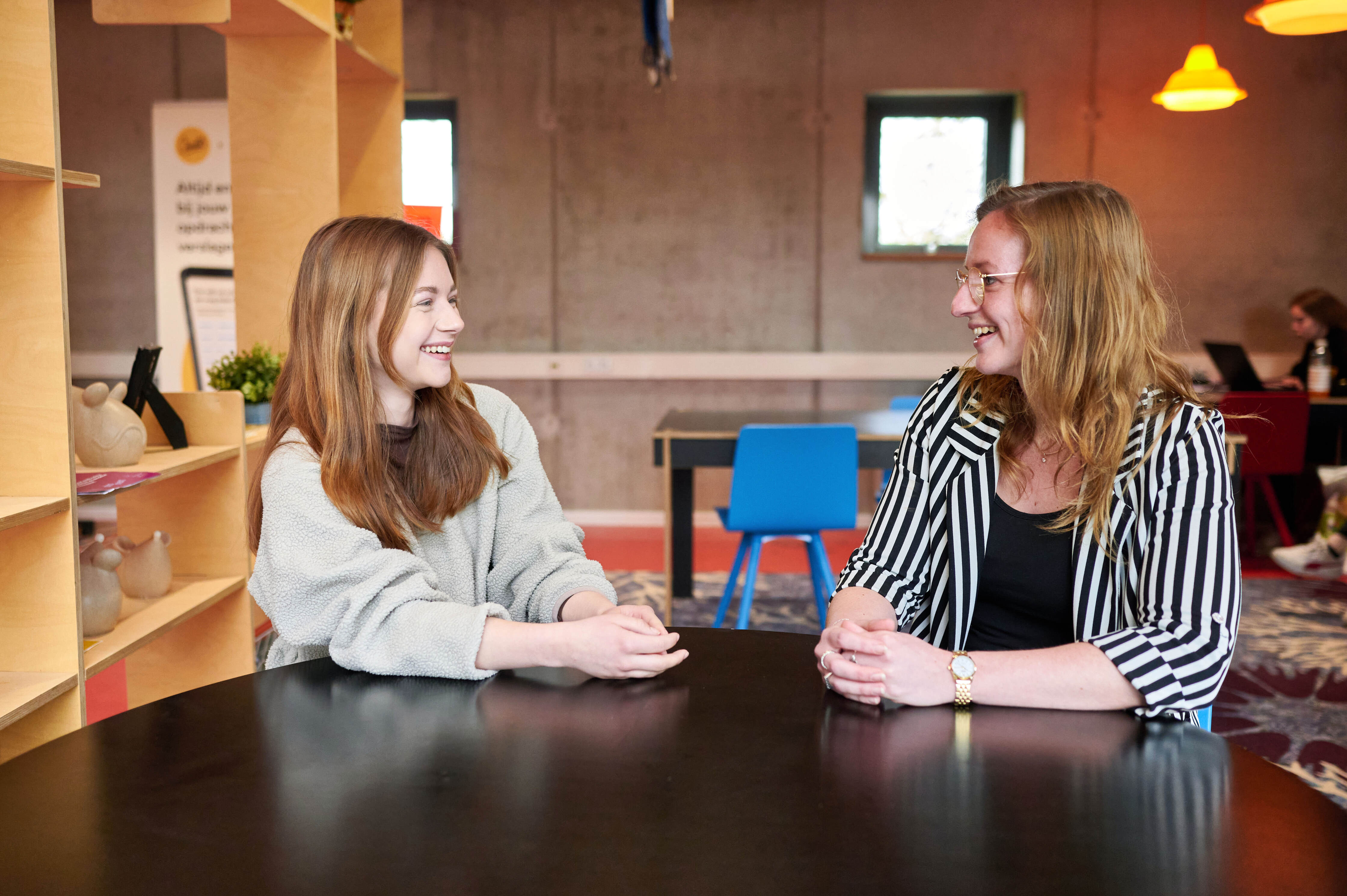 Twee personen in gesprek aan tafel, gericht op begeleiding en ondersteuning tijdens de opleiding