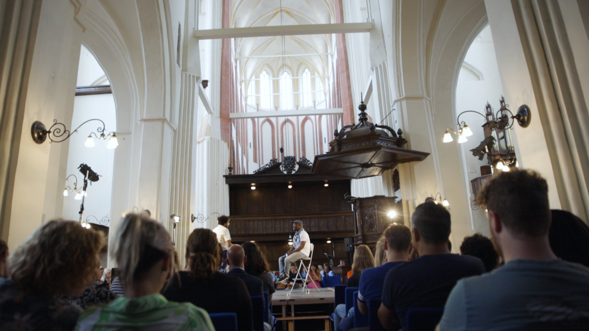 Studenten en medewerkers luisteren naar een spreker tijdens het Keti Koti-event in de A-Kerk.