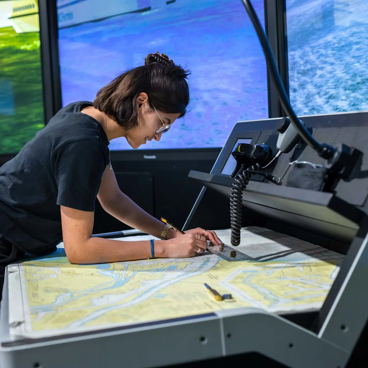 Student controleert kaart in nautische simulator voor kleine schepen bij Maritiem officier opleiding