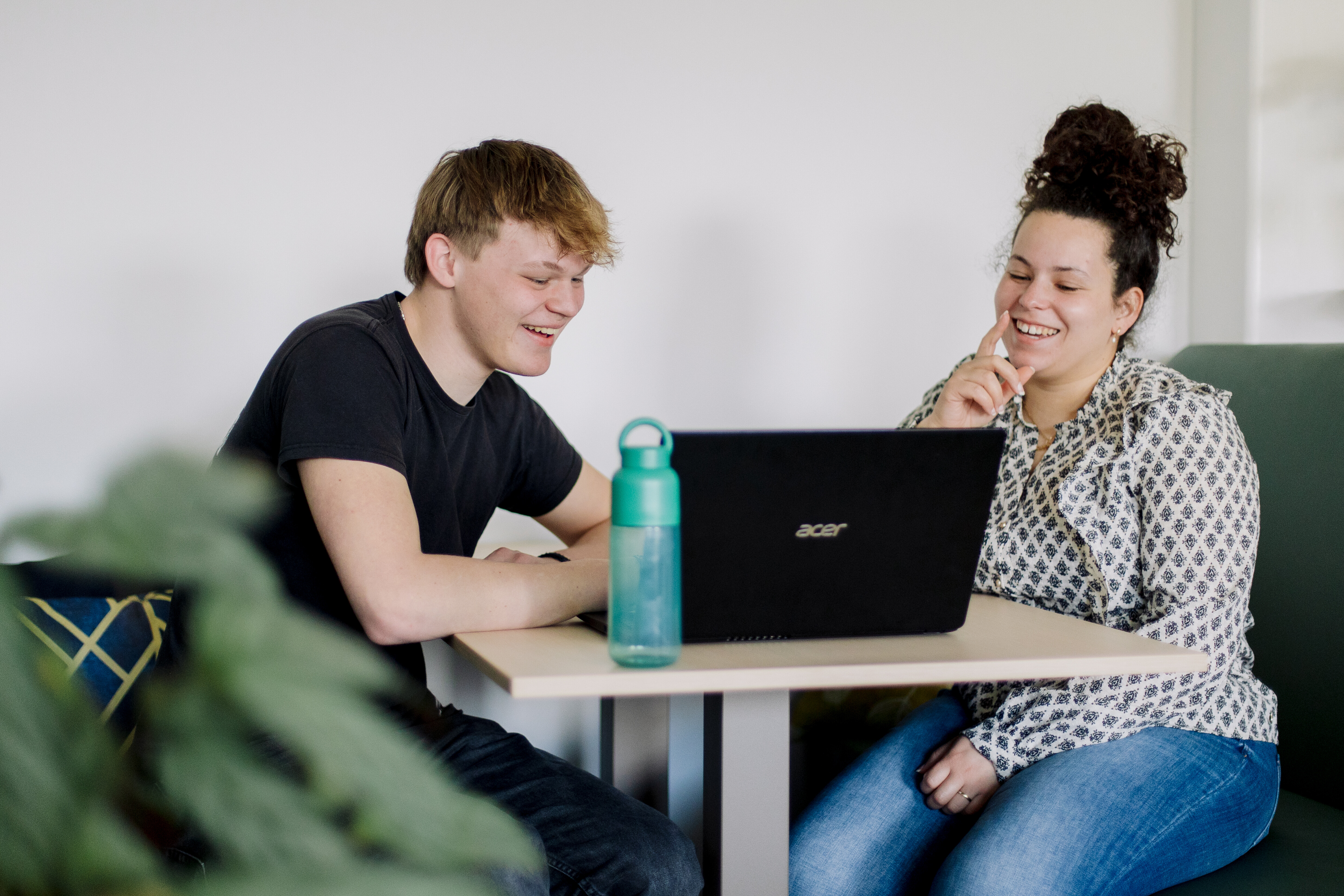 Twee studenten werken samen aan een laptop tijdens een studiegesprek ter voorbereiding op een opdracht.