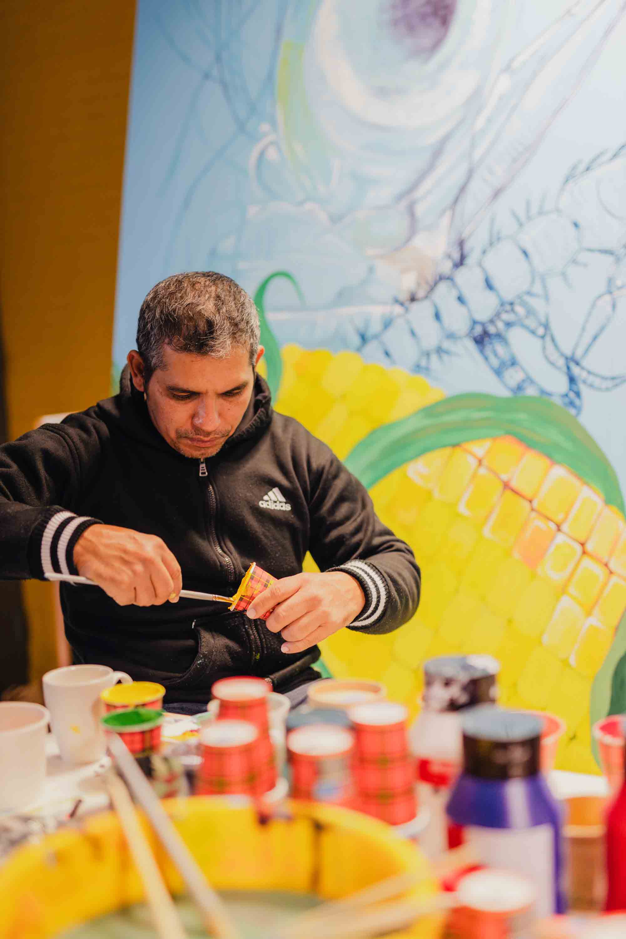 Kunstmaker bezig met het voorbereiden van verf voor een watergerelateerde muurschildering binnen een creatief project