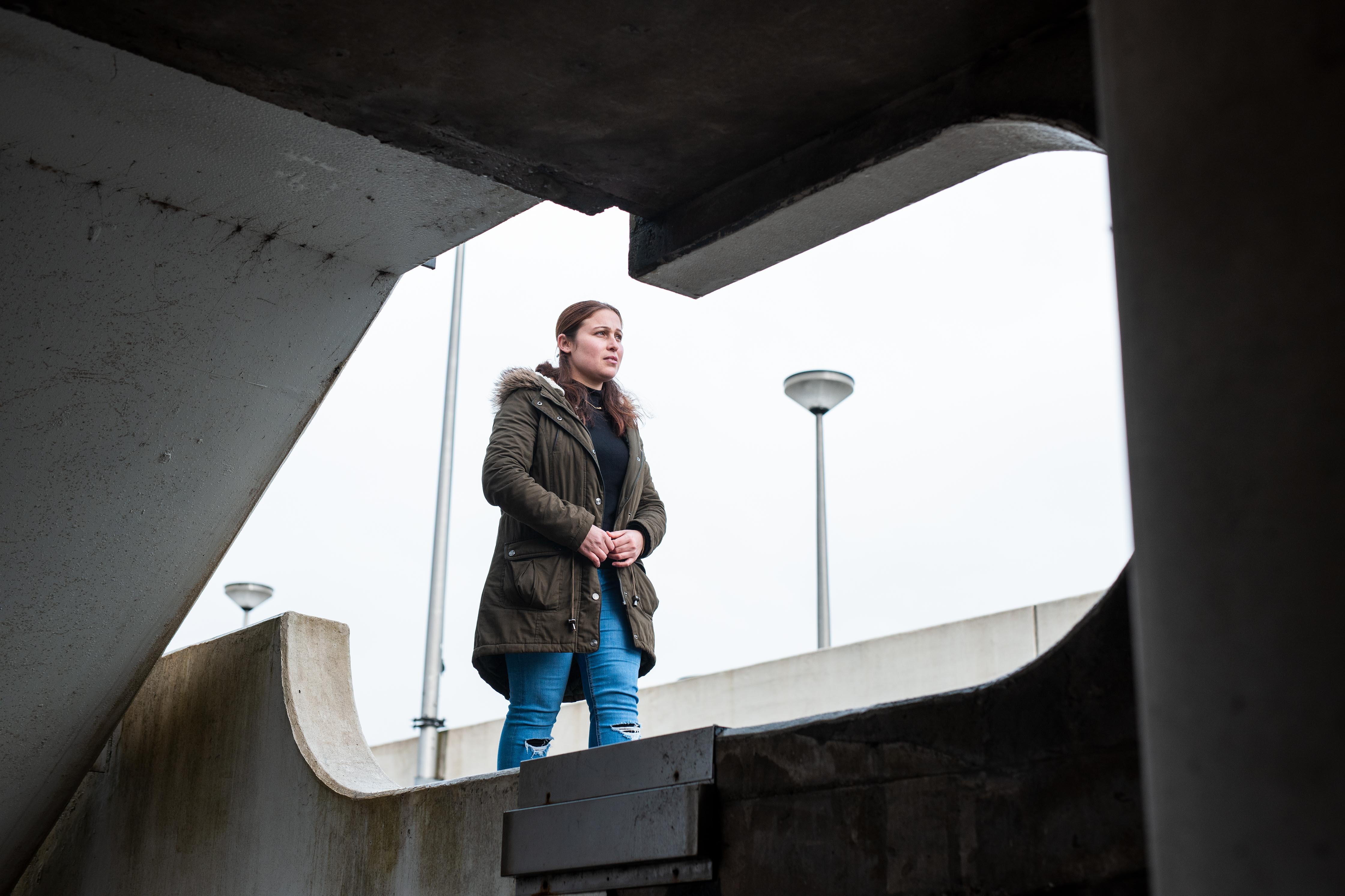 Een student staat buiten in winterkleding, kijkend naar de horizon, wat hoop en doorzettingsvermogen symboliseert