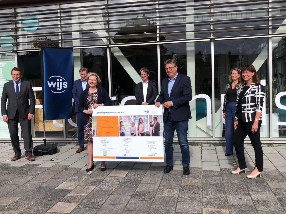 Onderwijsprofessionals poseren voor het pand van Noorderpoort met groot bord van Gronings studenten-project WIJS