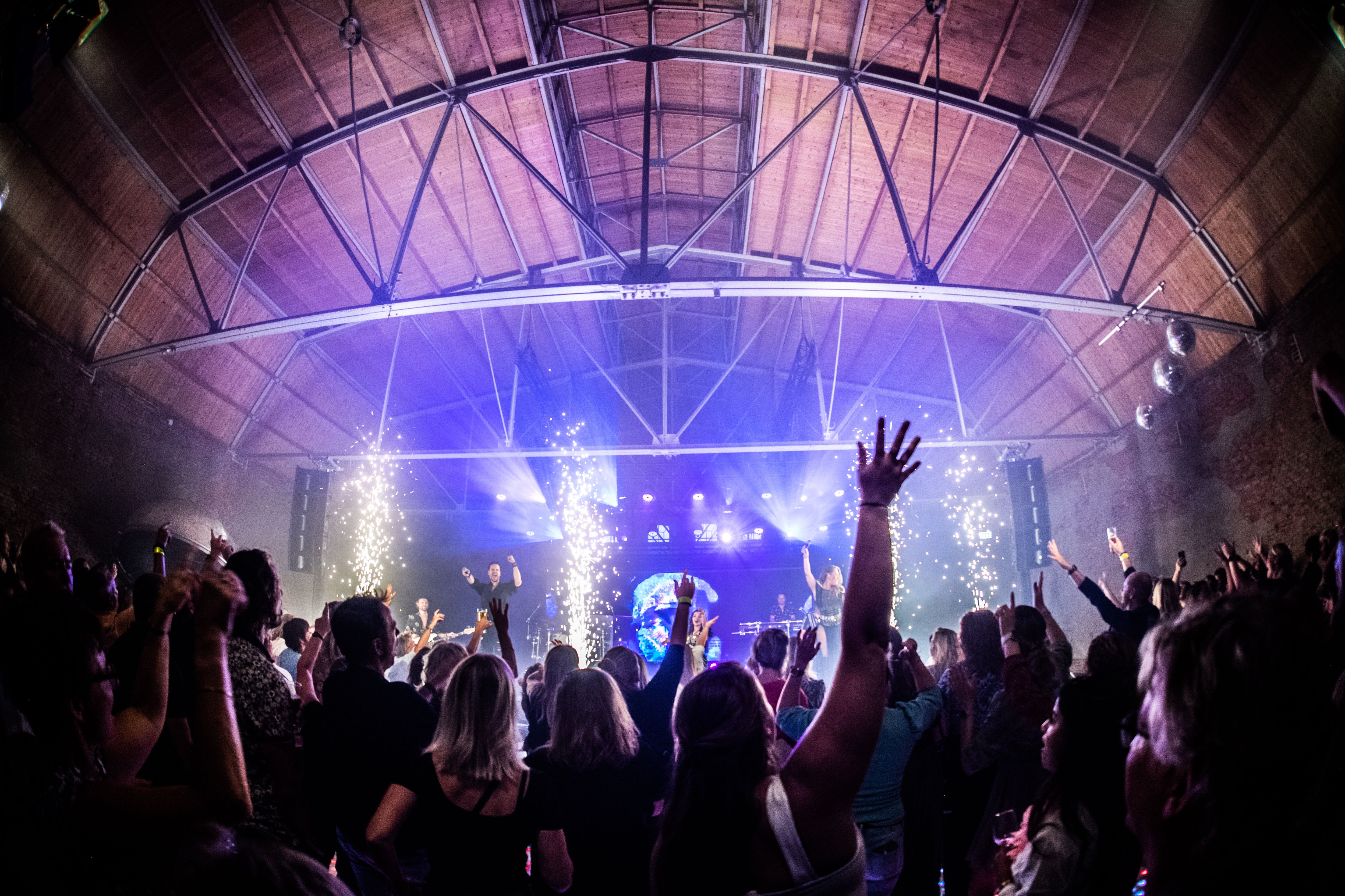 Groep bezoekers viert jubileum met muziek en lichtshow tijdens evenement van onderwijsorganisatie in grote zaal