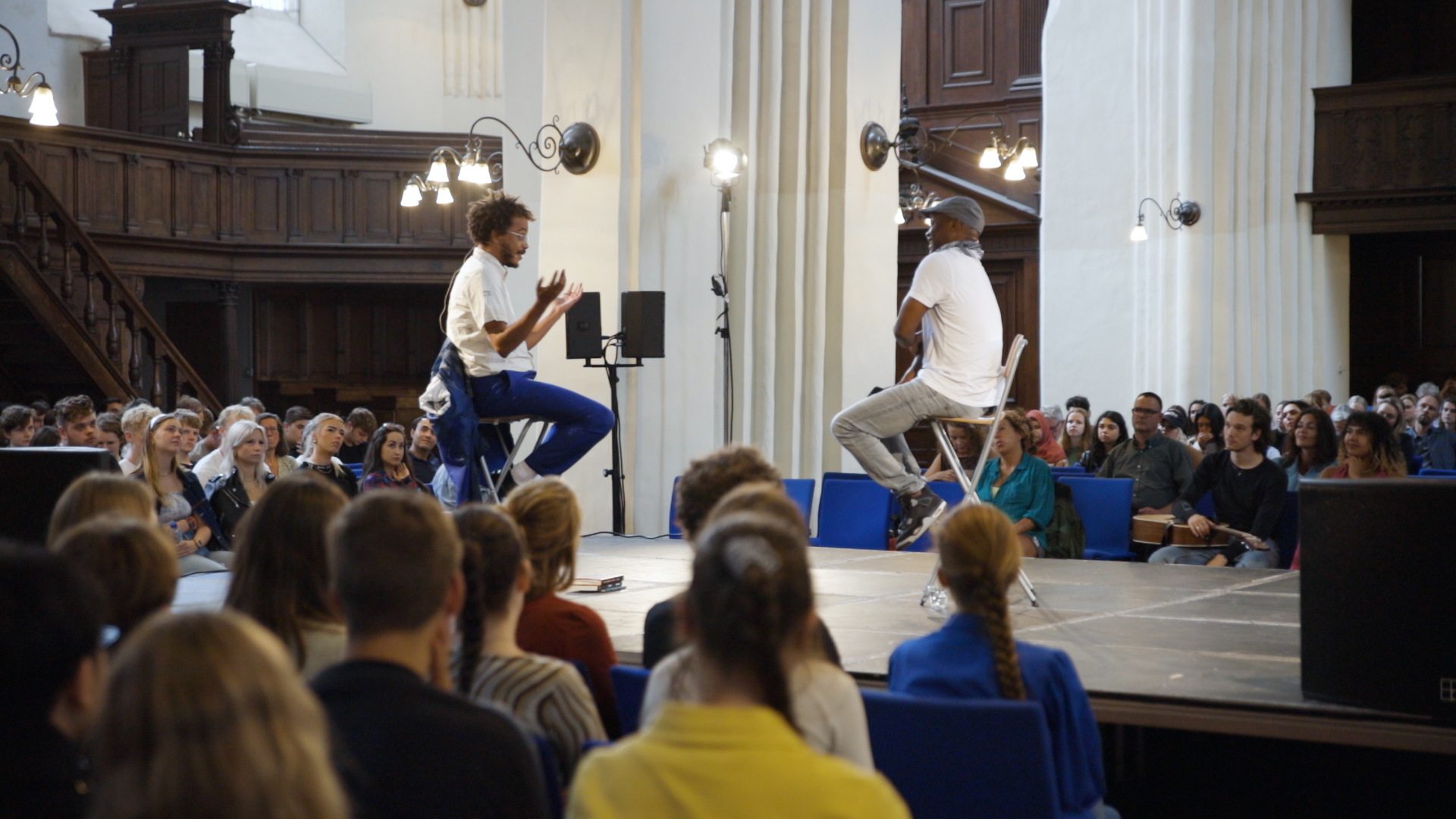 Presentatoren voeren een gesprek op een podium tijdens Keti Koti-event voor studenten en medewerkers van Noorderpoort.
