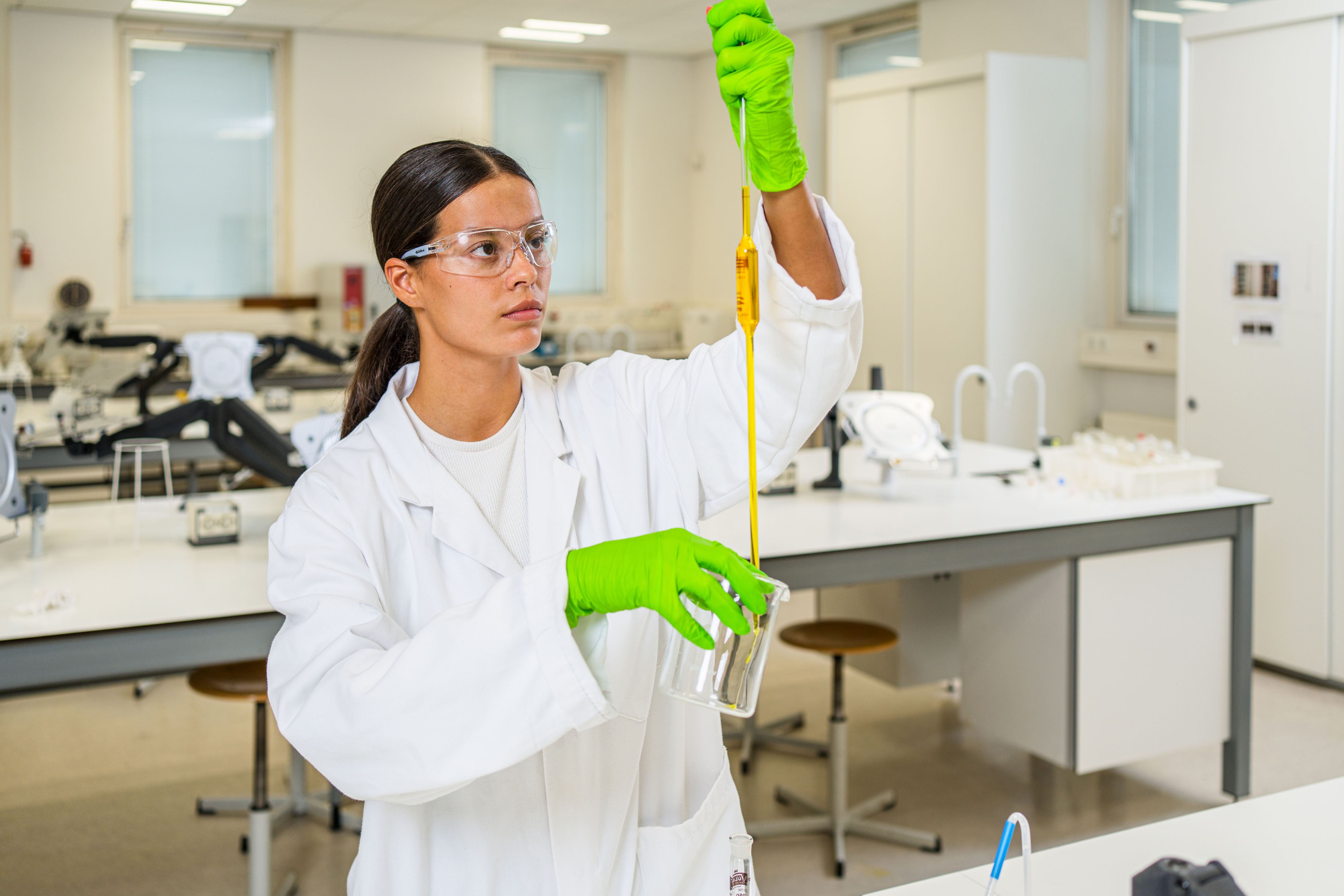 Student werkt geconcentreerd met pipet en reageerbuis in modern laboratorium voor procestechniek