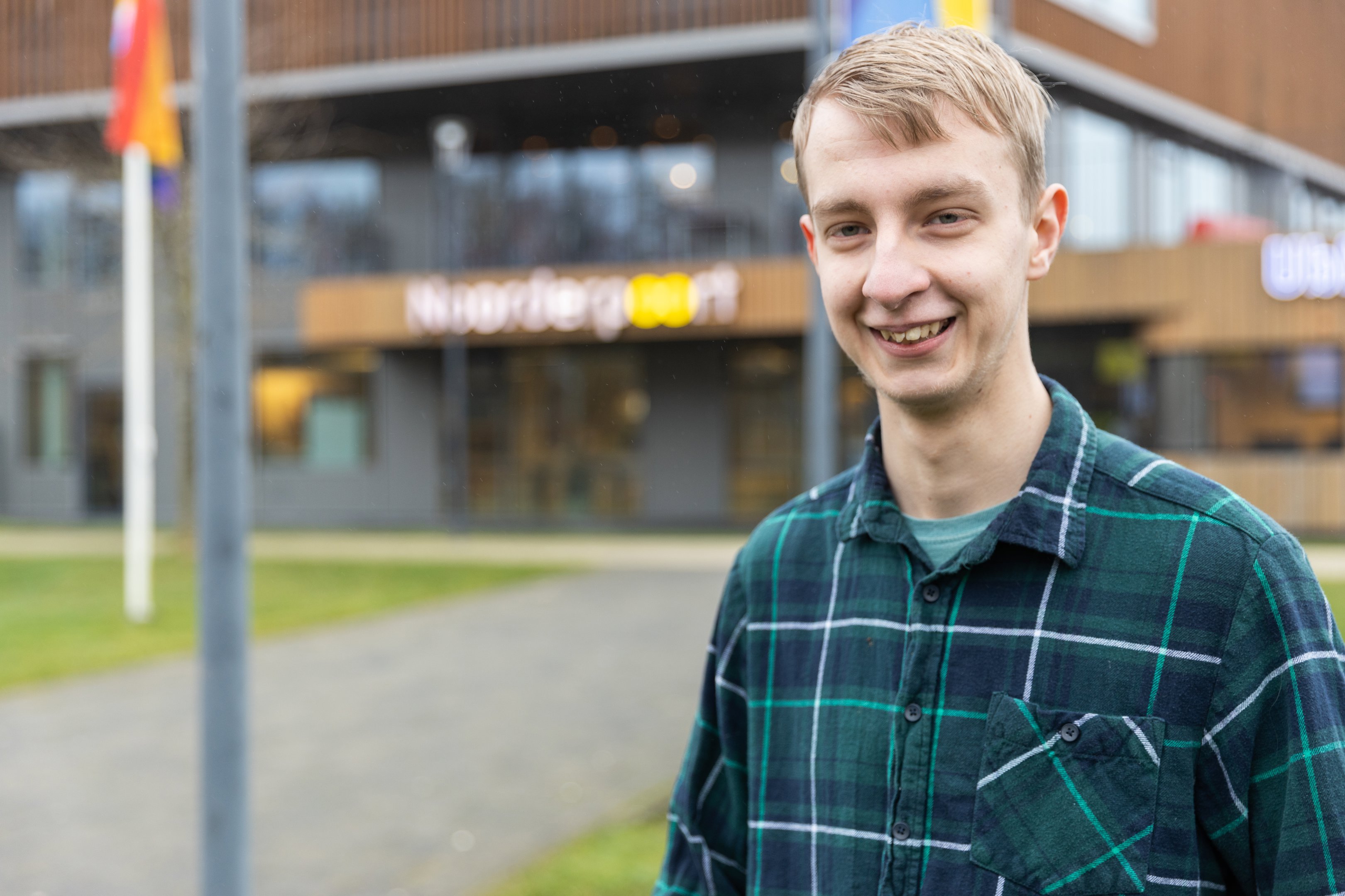 Dennis, lid van het inspiratieteam NEXT, staat voor de hoofdingang van Noorderpoort in Stadskanaal.