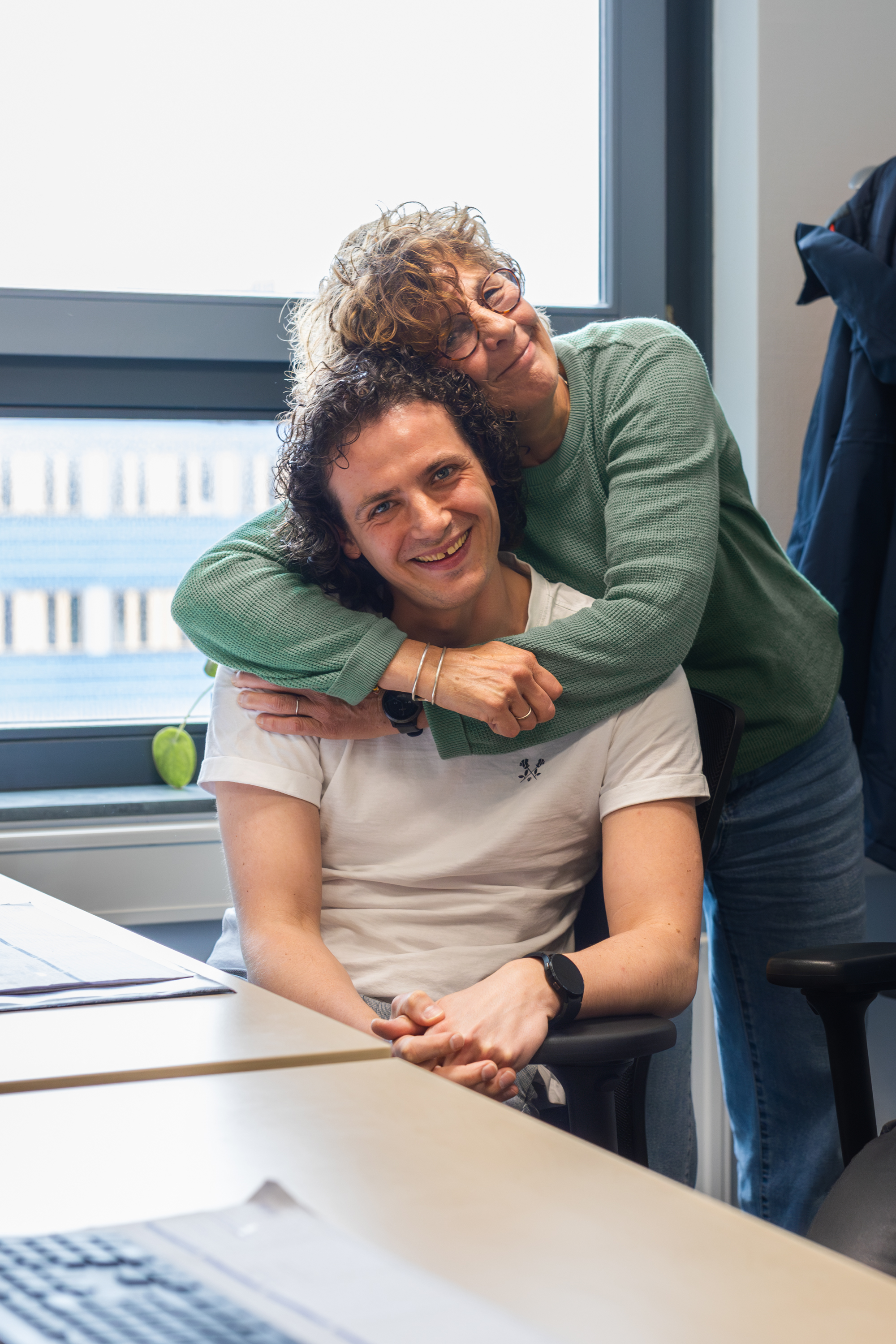 Twee studenten delen een warm moment in een klaslokaal bij Noorderpoort, verbonden door studievriendschap.