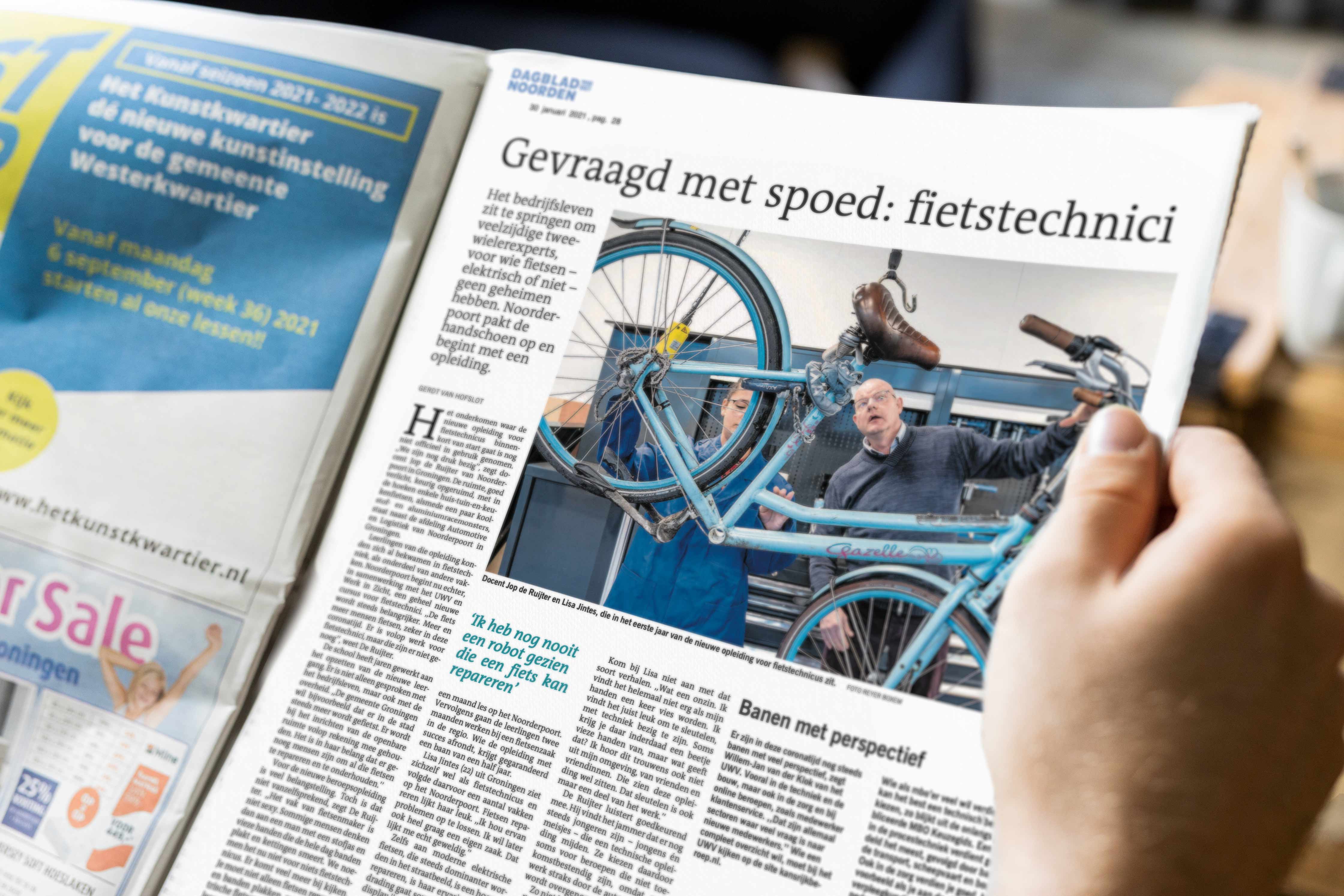 Krantenartikel over een fietsenmaker die een fiets repareert, met focus op vakmanschap in de techniek.