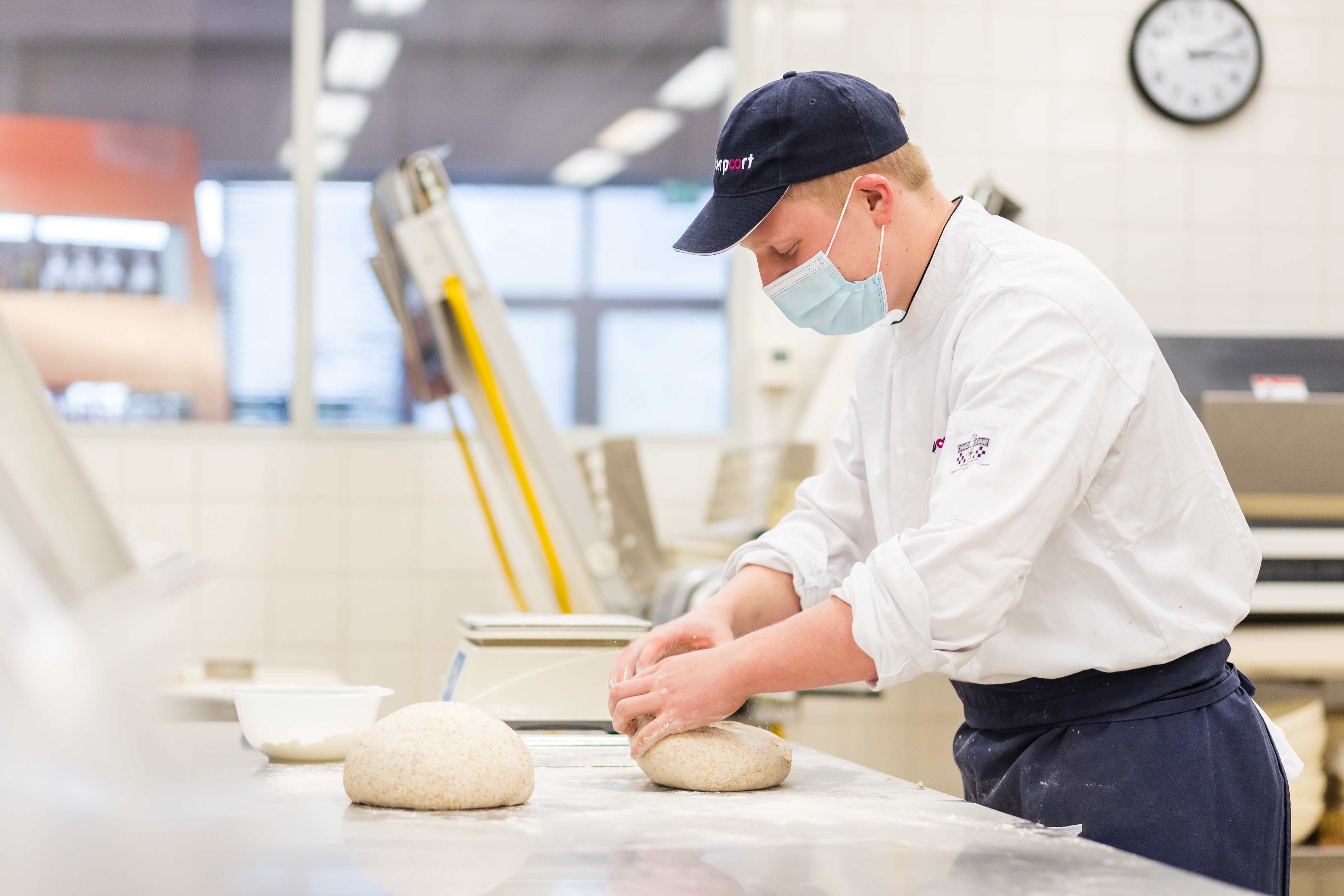 Student bakkersopleiding bereidt deeg voor in een professionele werkomgeving