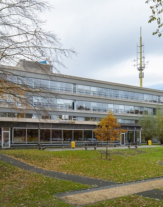 Exterieur van het onderwijsgebouw aan Winschoterdiep 50 met groene buitenruimte en wandelpaden