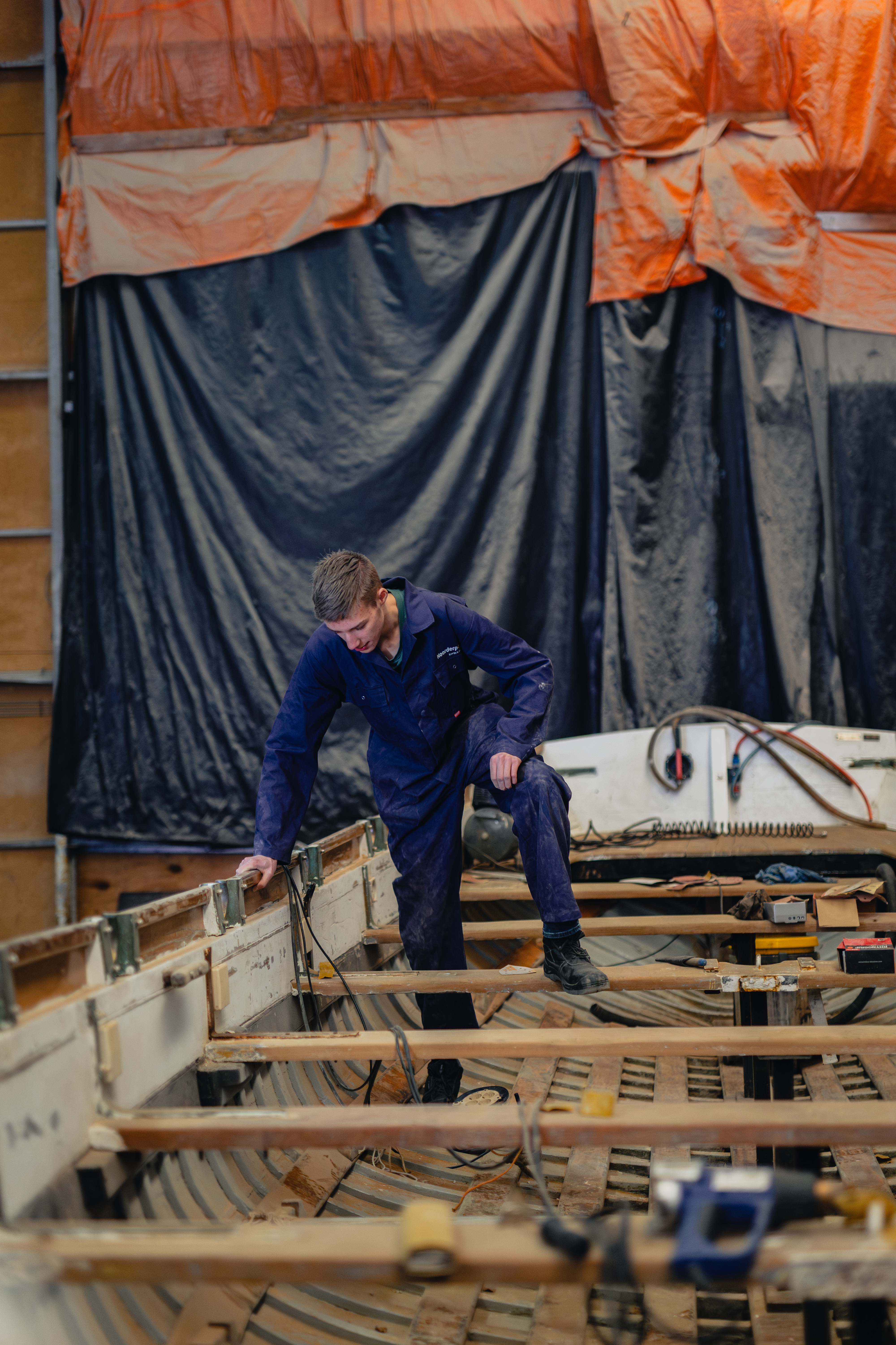 Maritiem student werkt aan het renoveren van een houten schip in een werkplaats van Noorderpoort