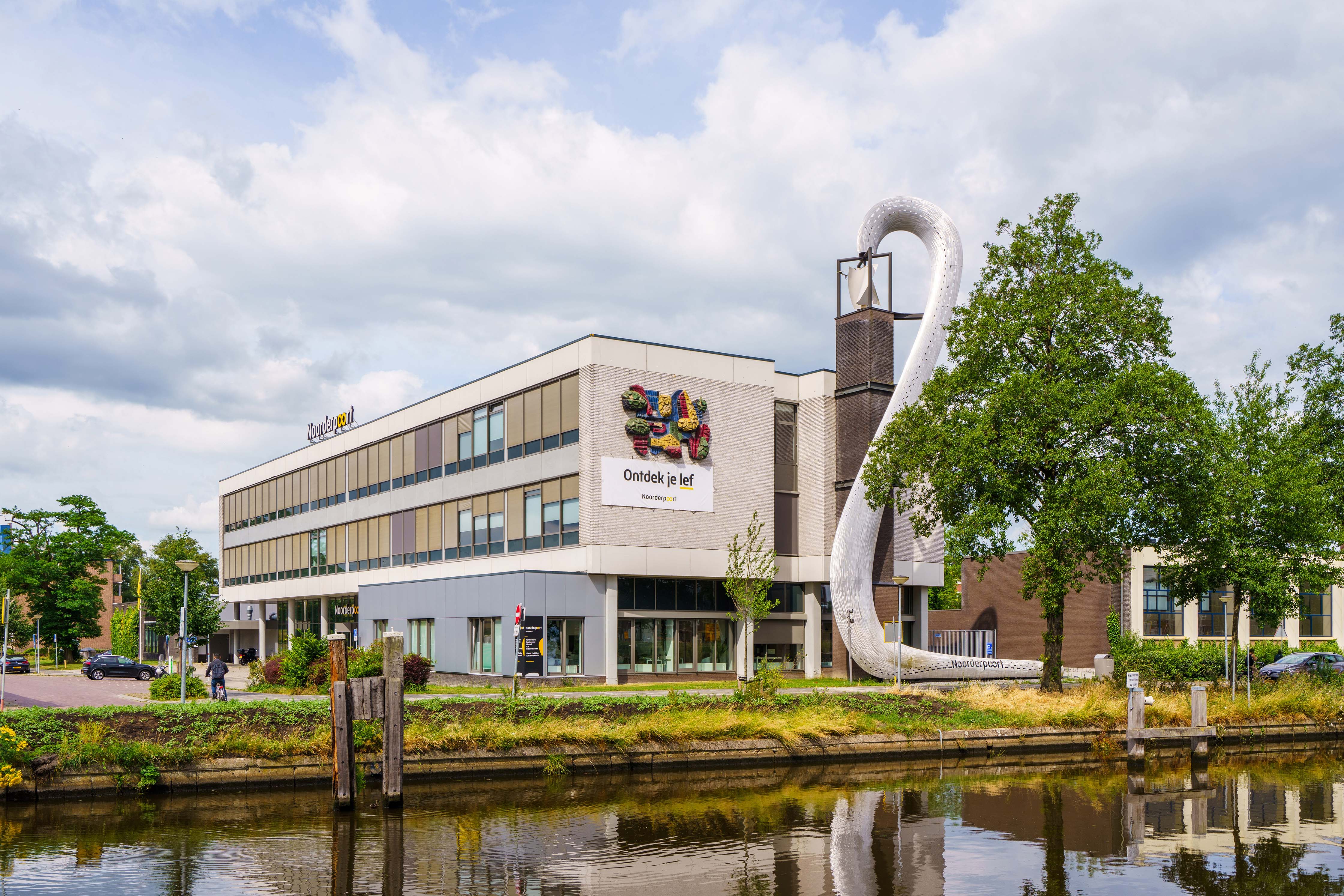 Onderwijslocatie Noorderpoort Muntinglaan 3 in Groningen met kenmerkende kunstinstallatie bij water