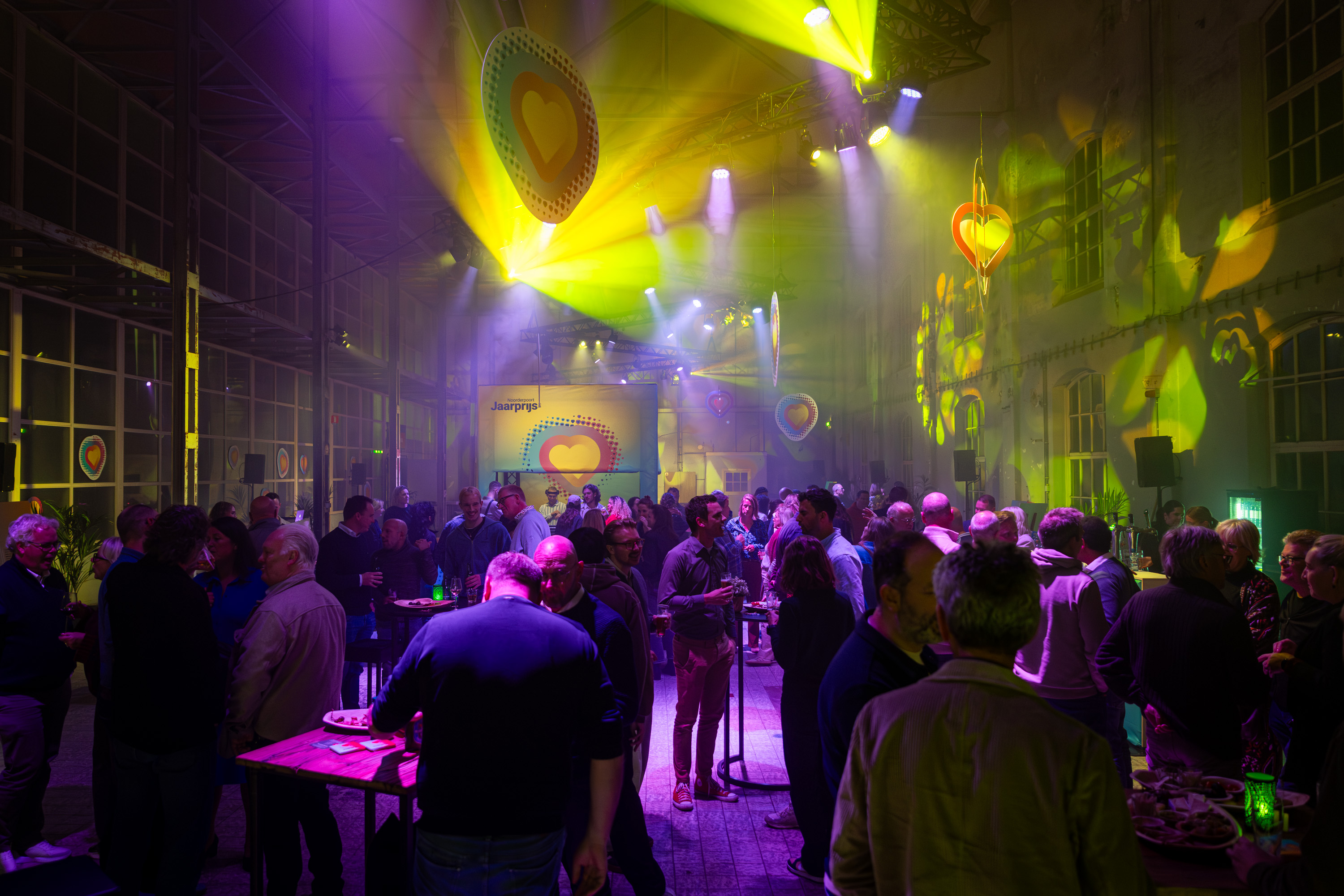 Groep bezoekers netwerkevenement Noorderpoort Jaarprijs 2025 in grote zaal met sfeerverlichting